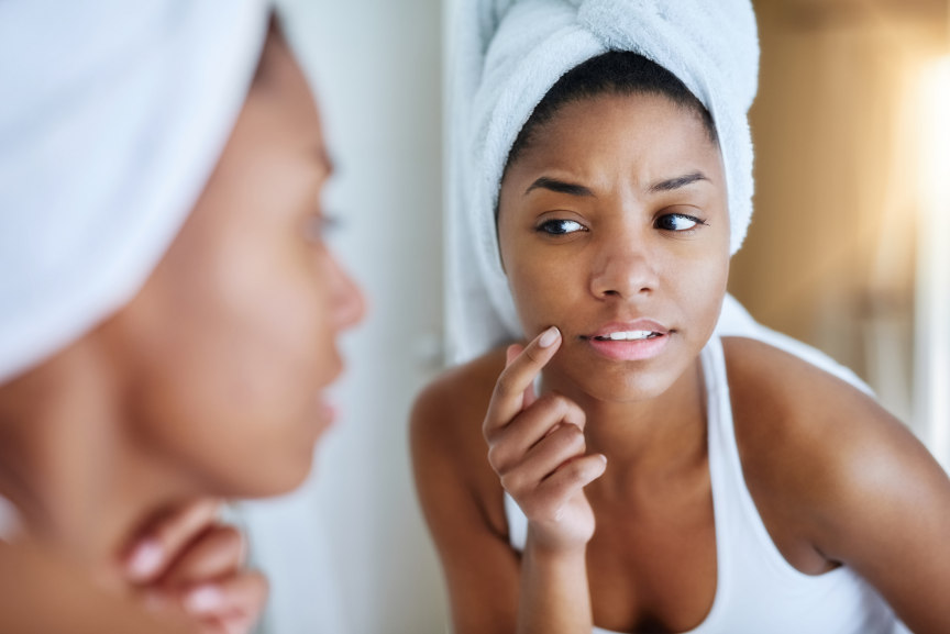 Woman examining skin in mirror before visiting a washington dc dermatology practice